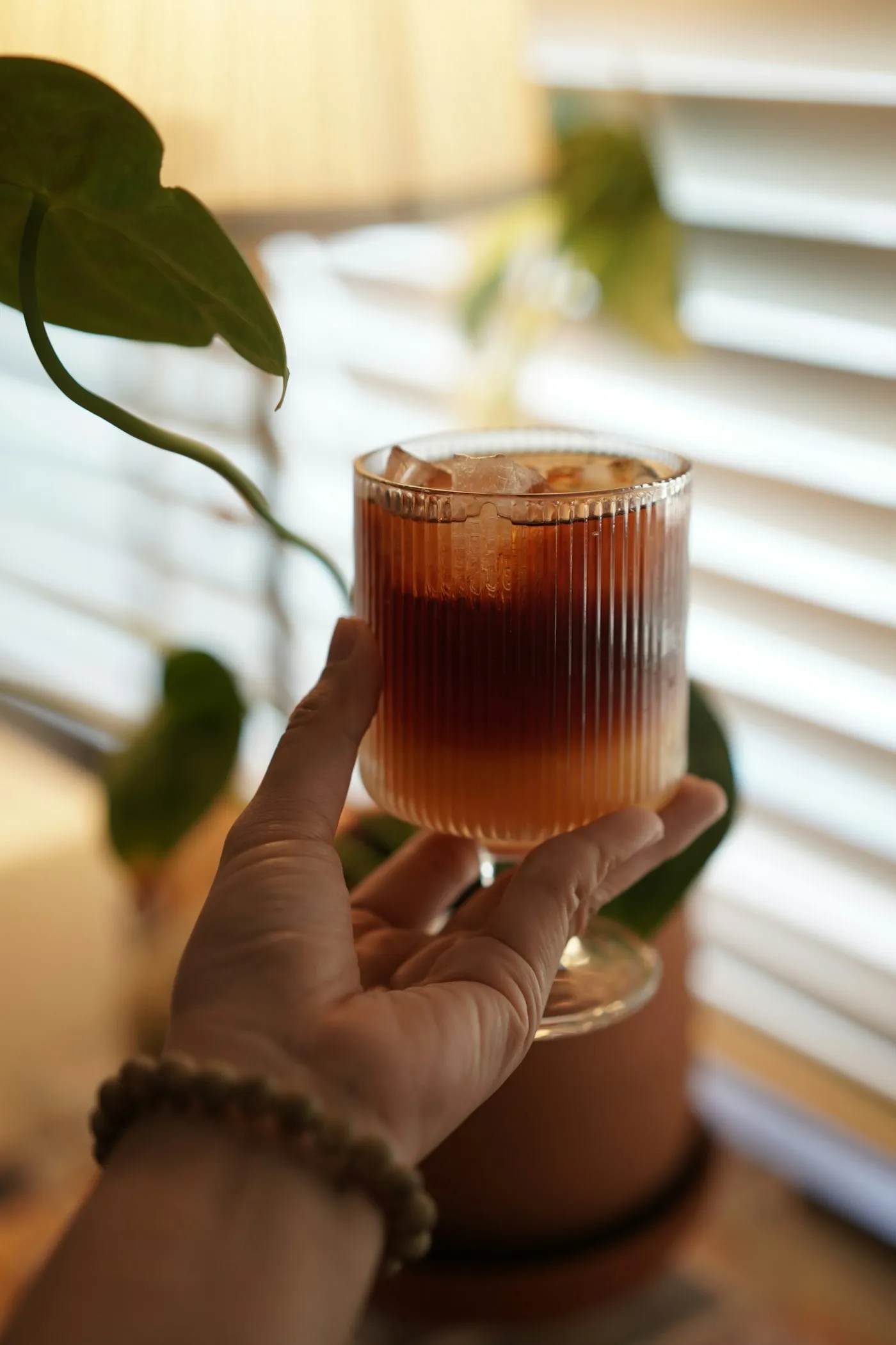 Hand holding a layered iced coffee drink similar to a 7 Brew Original breve